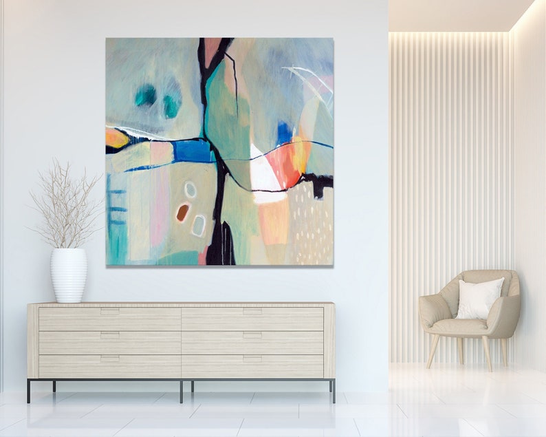 May include: Abstract painting with geometric shapes in shades of blue, green, pink, and orange. The painting is framed and hanging on a white wall above a wooden dresser.