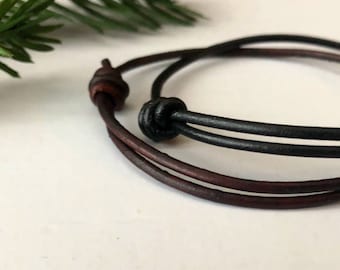 May include: A brown and black leather bracelet with a knot detail.