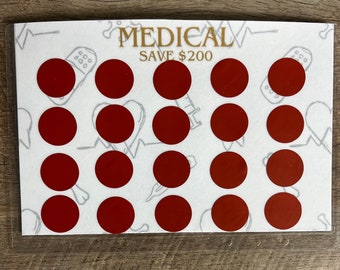 Puede incluir: Una tarjeta blanca con el texto "MEDICAL SAVE 200 €" impreso en dorado. La tarjeta tiene 18 círculos rojos dispuestos en una cuadrícula.