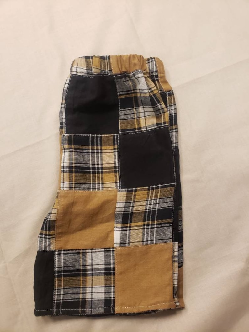 May include: Patchwork shorts with a black and yellow plaid pattern. The shorts have an elastic waistband and are made of a soft, comfortable fabric.