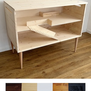 May include: A wooden pet cage with a ramp and a shelf. The cage is made of natural wood and has a light wood finish. The cage is on four legs and has a modern design.