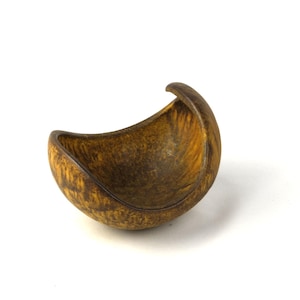 以下が含まれることがあります： 三日月型のユニークな形をした茶色のセラミックボウル。ボウルは質感のある表面と自然な木目模様をしています。