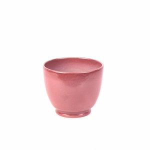 May include: A small, pink ceramic cup with a rounded bottom and a slightly flared rim.