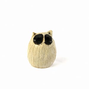 May include: A small ceramic figurine of an owl with black eyes and a white speckled body.