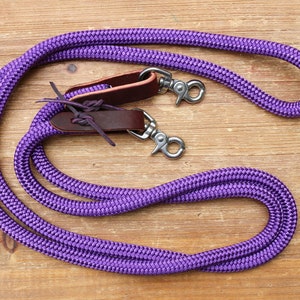 May include: Purple braided leather reins with brown leather keepers and silver snap hooks.