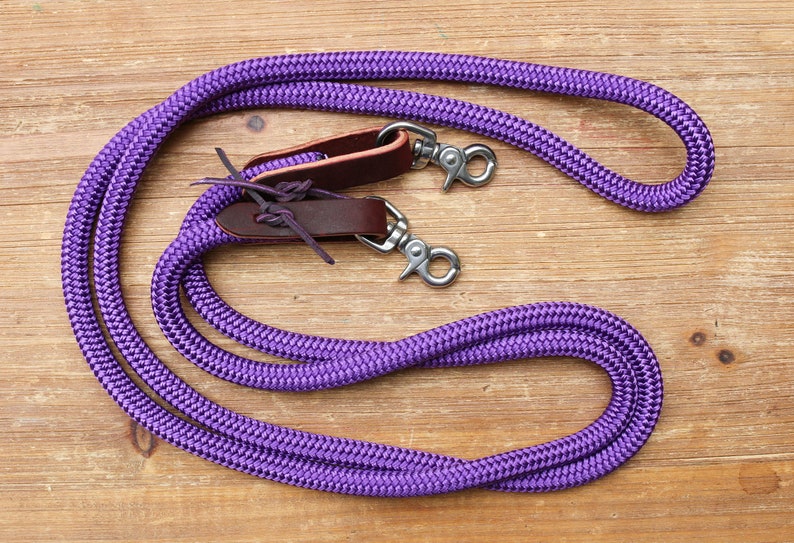 May include: Purple braided leather reins with brown leather keepers and silver snap hooks.