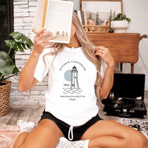 May include: White t-shirt with a black and white illustration of a lighthouse with the text "Scituate Lighthouse 1811 Massachusetts" printed on the front.