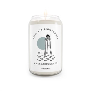 May include: A white candle in a glass jar with a black and white illustration of a lighthouse with the text "Scituate Lighthouse 1811 Massachusetts saltwater points" on the label.