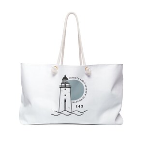 Op de afbeelding: Witte canvas draagtas met een zwart-witte illustratie van een vuurtoren met de tekst "Minots Light 42°16'11.7"N 70°45'10.5"W 143" erop gedrukt.