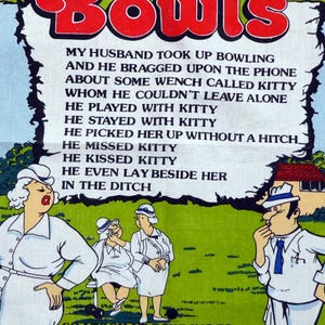 May include: A white tea towel with a red border featuring a cartoon scene about bowls. The towel has the word "Bowls" in large red letters and includes text about a husband and "Kitty". The design is from Australia.