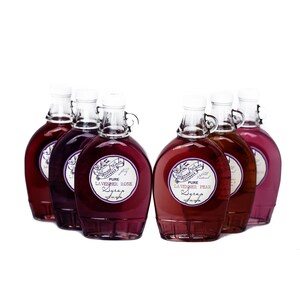 May include: Six glass bottles of lavender syrup with labels that read "The Lavender Twist" and "Pure All Natural Lavender Rose Syrup" and "Pure All Natural Lavender Pear Syrup".