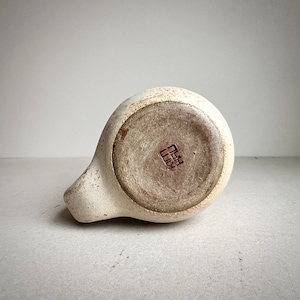 May include: A white ceramic pitcher with a brown glaze on the bottom. The pitcher has a small, square, brown stamp on the bottom that reads "田口".