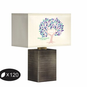 May include: A rectangular lamp with a dark brown base and a cream-colored lampshade. The lampshade features a tree design with purple, blue, and green leaves, a heart-shaped cutout, and the text "Manuela & Steven 5-10-2017".