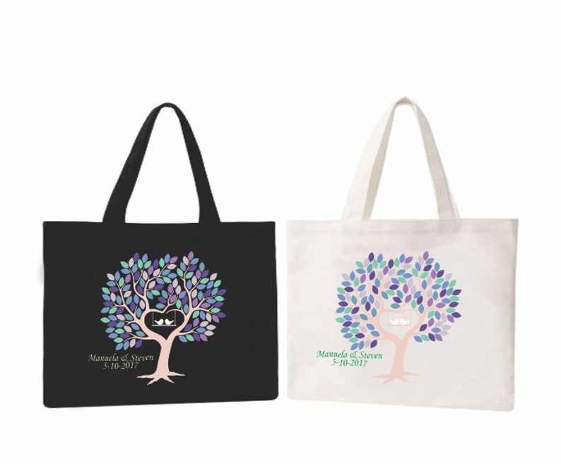 May include: Two tote bags, one black and one white, each featuring a tree design with a heart-shaped swing and two birds. The tree has purple, blue, and green leaves. The text "Manuela & Steven 5-10-2017" is printed below.