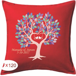 May include: Red decorative pillow with a tree design. The tree has a heart-shaped trunk with two white birds on a swing. The leaves are various shades of blue, purple, and green. The names "Manuela & Steven" and the date "5-10-2017" are printed on the pillow.