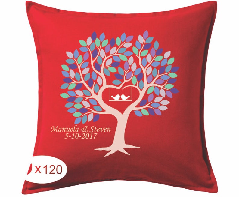 May include: Red decorative pillow with a tree design. The tree has a heart-shaped trunk with two white birds on a swing. The leaves are various shades of blue, purple, and green. The names "Manuela & Steven" and the date "5-10-2017" are printed on the pillow.