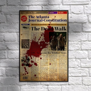May include: A framed newspaper print of "The Atlanta Journal-Constitution" with the headline "The Dead Walk." The print features a large blood splatter and images of zombies, set against a brick wall.