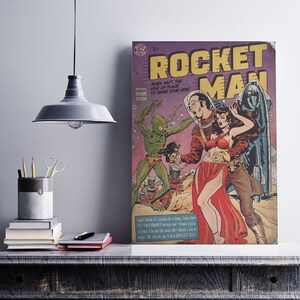 Peut inclure: Une couverture de bande dessinée vintage représentant un homme en combinaison spatiale tenant une femme en robe rouge. La couverture est intitulée "Rocket Man" et présente un extraterrestre vert en arrière-plan. La bande dessinée est en bon état avec quelques signes d'usure.