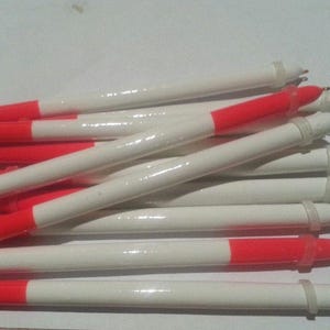 May include: A group of white and red fishing bobbers with a loop at the end. The bobbers are made of a lightweight material and have a bright red band.