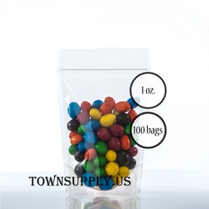 May include: A pack of 100 clear plastic stand-up pouches with a zipper closure. Each pouch is 1 ounce and filled with colorful candy. The pouches are labeled "1 oz." and "100 bags".