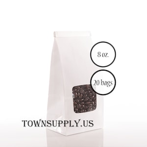 May include: A white paper bag with a clear window displaying dark brown coffee beans. The bag is labeled with "8 oz." and "20 bags" in black circles. The website "TOWNSUPPLY.US" is printed at the bottom of the bag.