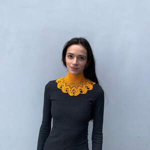 Puede incluir: Una mujer con un collar de ganchillo amarillo mostaza sobre una camisa negra de cuello alto.