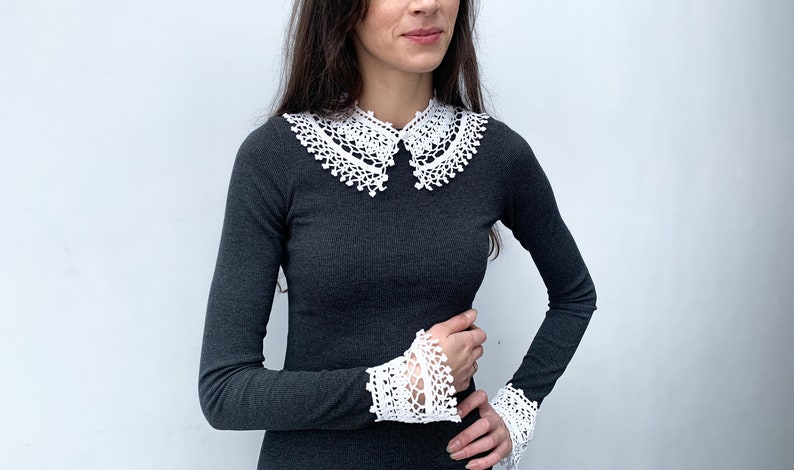 May include: A black long-sleeved shirt with a white crocheted collar and matching cuffs.