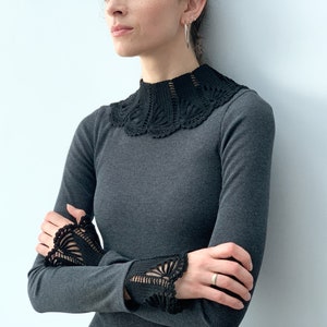 May include: A charcoal gray long-sleeved shirt with a black crocheted collar and cuffs.