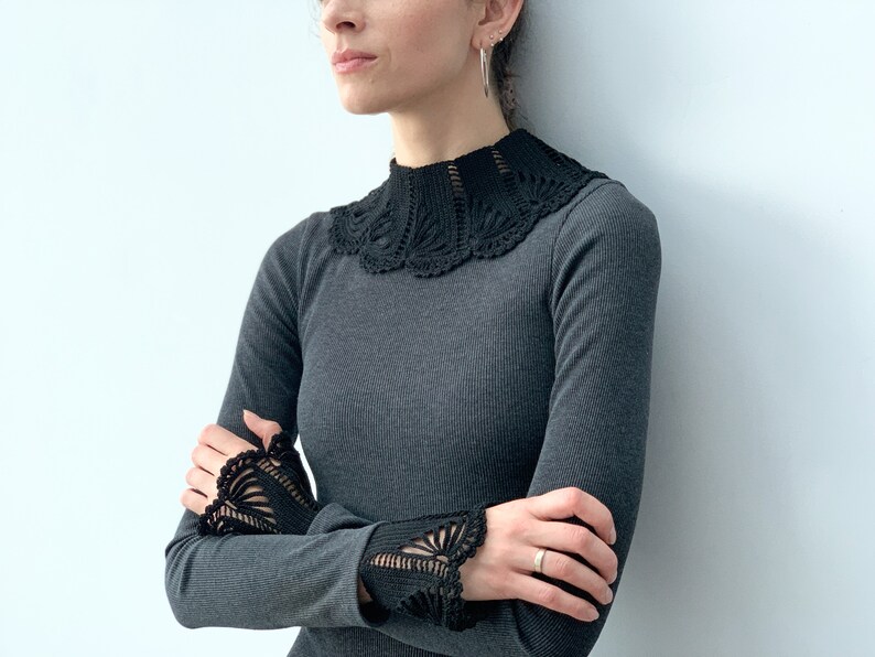May include: A charcoal gray long-sleeved shirt with a black crocheted collar and cuffs.