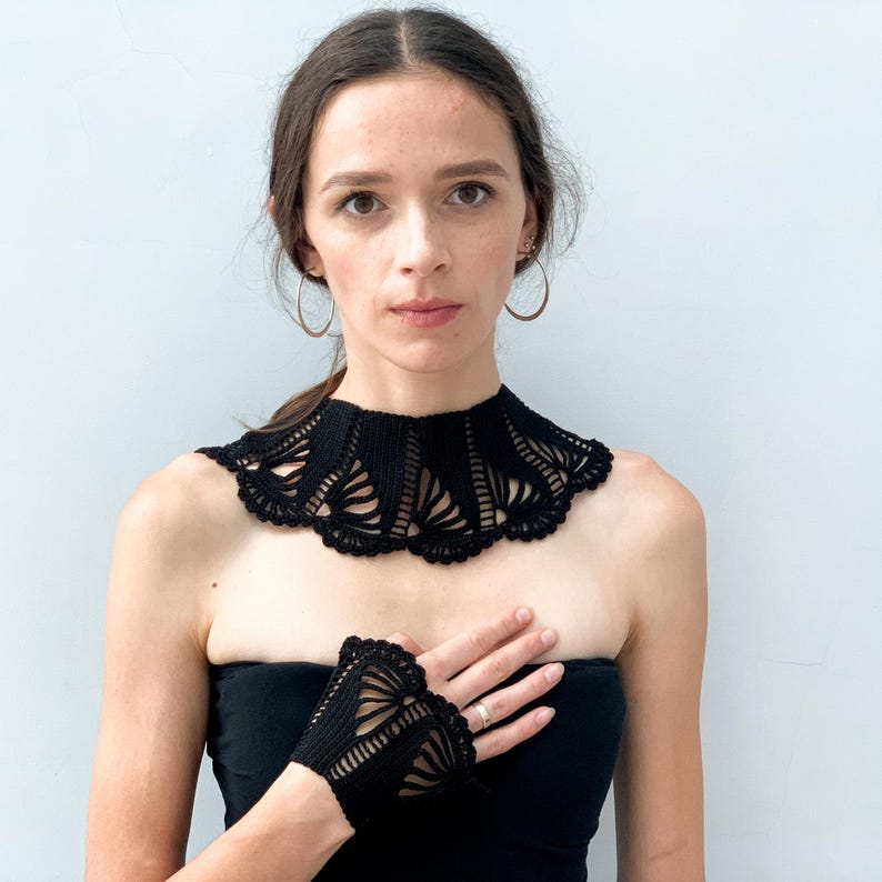 May include: A black crocheted collar and matching fingerless gloves. The collar is wide and has a scalloped edge. The gloves are short and have a delicate lace pattern.