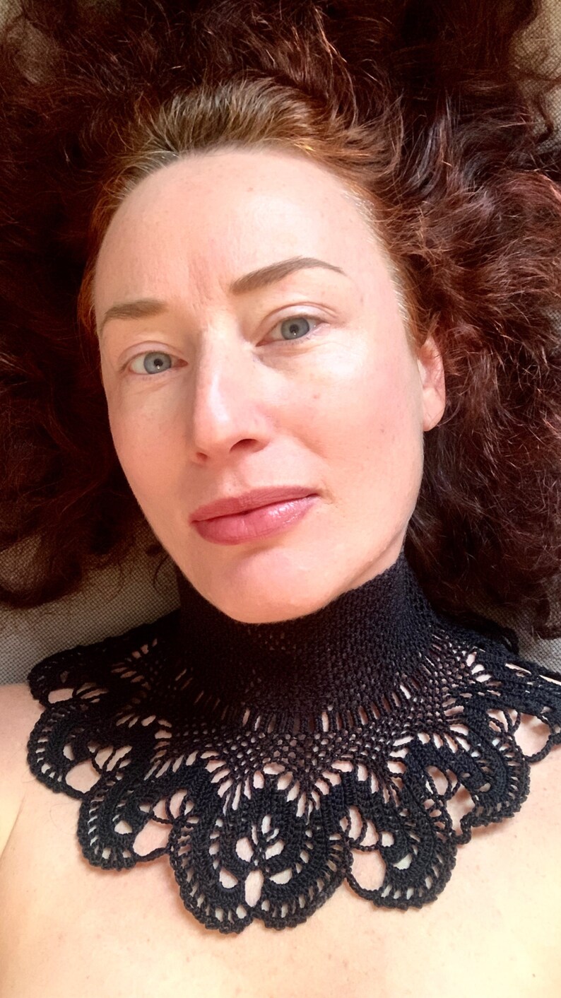 Puede incluir: Una mujer con el pelo largo y rizado rojo que lleva un collar de encaje de ganchillo negro.