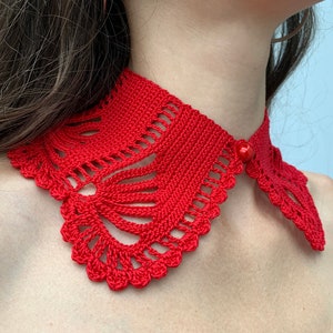 May include: A red crocheted collar with a decorative button. The collar is made with a delicate, lacy pattern.