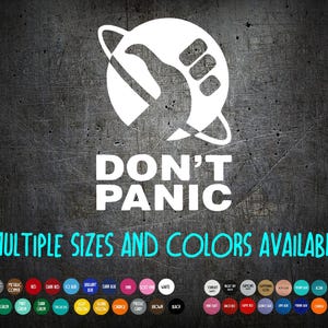 May include: White graphic with the text "DON'T PANIC" and a stylized hand and planet design. Below, the text "MULTIPLE SIZES AND COLORS AVAILABLE" is written in teal. A color palette is displayed at the bottom.