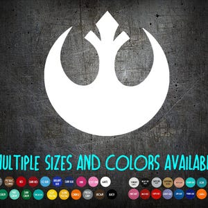May include: White graphic of a stylized symbol on a dark, textured background. The symbol is a crescent shape with a central upward-pointing element. Text at the bottom reads "MULTIPLE SIZES AND COLORS AVAILABLE" with a color palette.