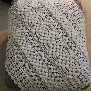 Peut inclure: Une nappe en crochet blanche avec un motif délicat et complexe. La nappe a un bord festonné et un design tissé.