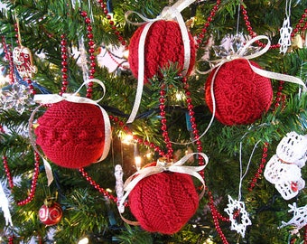 Könnte beinhalten: Rote gestrickte Weihnachtskugeln, die an einem grünen Weihnachtsbaum mit roter und weißer Perlenkette hängen.