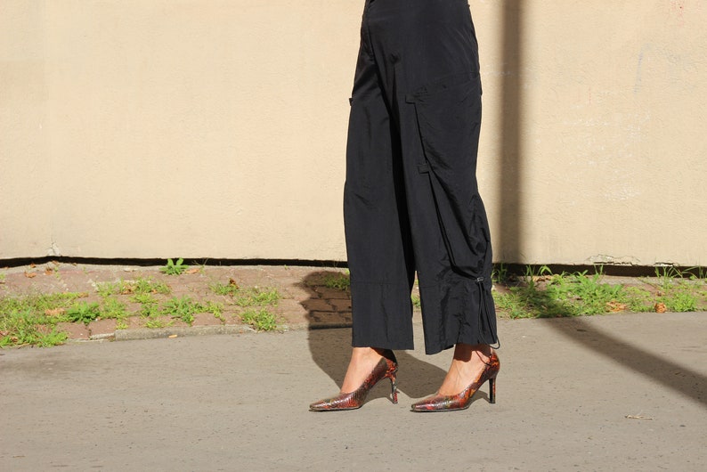 Puede incluir: Una persona con pantalones negros y tacones altos con estampado rojo y negro.