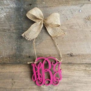 May include: A pink wooden monogram with the letters "HBG" in a cursive font. The monogram is hanging from a piece of twine with a hessian bow.