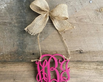 May include: A pink wooden monogram with the letters "HBG" in a cursive font. The monogram is hanging from a piece of twine with a burlap bow.
