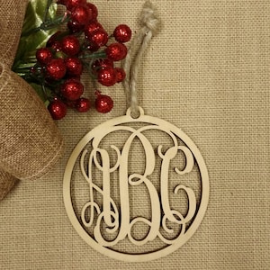 May include: A wooden Christmas ornament with a monogram of the letters "ABC" cut out in a decorative script font. The ornament is round and has a twine hanger.
