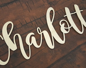 May include: A wooden sign with the name "Charlotte" written in cursive script.