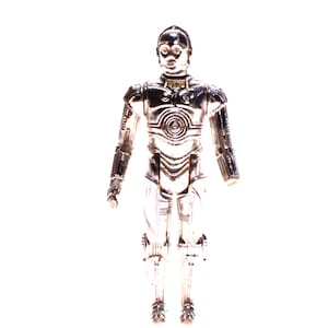 Peut inclure: Figurine argentée de C-3PO, personnage de Star Wars. La figurine est debout, les bras le long du corps. Le design détaillé révèle des composants mécaniques et une finition métallique brillante. Objet de collection.