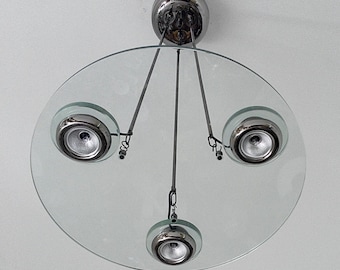 May include: A modern glass and chrome ceiling light fixture with three spotlights. The fixture has a circular glass shade and three chrome spotlights that are adjustable.