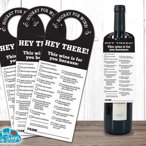 Op de afbeelding: Een zwarte en witte deurhanger met een uitsparing in de vorm van een wijnfles. De tekst luidt "Hooray for Wine! Hey There! This wine is for you because:" met een lijst met redenen om wijn te drinken.