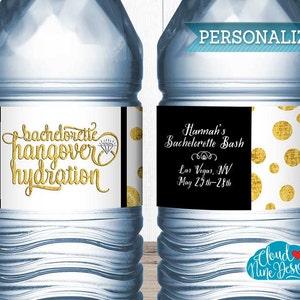 Op de afbeelding: Twee doorzichtige plastic waterflessen met zwarte en gouden etiketten. De etiketten hebben gouden stippen en tekst die "bachdorctie hangover hydration" en "Hannah's Bachelorette Bash Las Vegas, NV May 25th-28th" luidt.