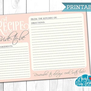 Op de afbeelding: Een afdrukbare receptkaart met een roze rand en een crèmekleurig interieur. De kaart bevat de tekst "A Recipe for the Bride-to-be" in elegant schrift. Het bevat secties voor ingrediënten en instructies, met de woorden "From the kitchen of:" en "Remember to always cook with love!"