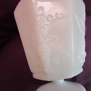 May include: White milk glass pedestal bowl with an embossed grapevine design. The bowl has a square base and a round top.