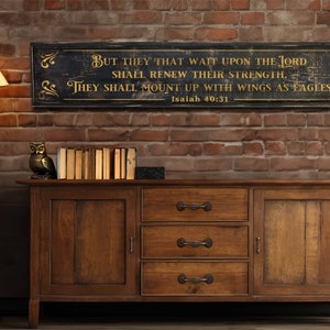 May include: A rustic wooden sign with a black background and gold lettering. The sign features a bible verse from Isaiah 40:31, "But they that wait upon the Lord shall renew their strength, they shall mount up with wings as eagles."