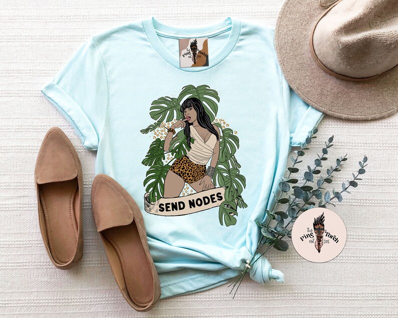 K&ouml;nnte beinhalten: Hellblaues T-Shirt mit einem Aufdruck einer Frau in einer Dschungelkulisse. Die Frau tr&auml;gt einen Bikini mit Leopardenmuster und ein wei&szlig;es Oberteil. Der Text "SEND NODES" ist unter dem Aufdruck gedruckt.