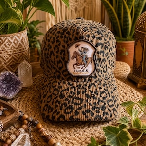 Czapka typu trucker z haftowanym motywem lamparta, czapka typu trucker z nadrukiem w panterkę, czapka typu snapback z imitacji sztruksu w panterkę, czapka baseballowa kowbojka